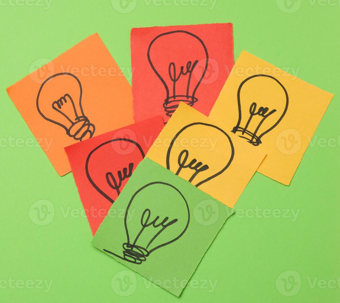 Drawn electric lamps on pieces of paper, the concept of searching for new solutions photo
