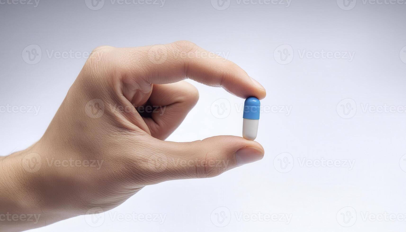 Close-up of a hand holding a blue and white capsule pill against a white background, emphasizing medication and health care. photo