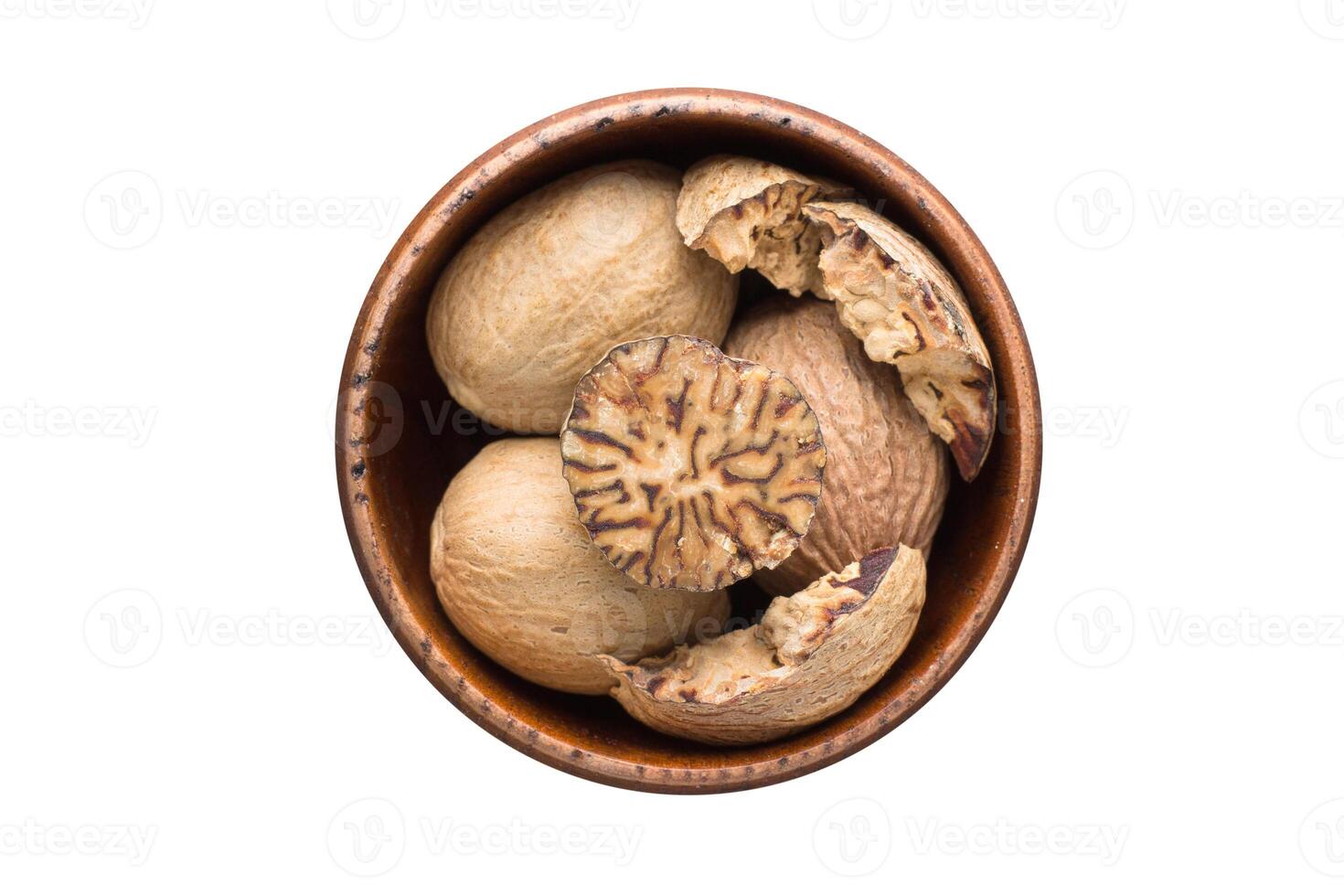 whole nutmeg spice in wooden bowl, isolated on white background. Seasoning top view photo