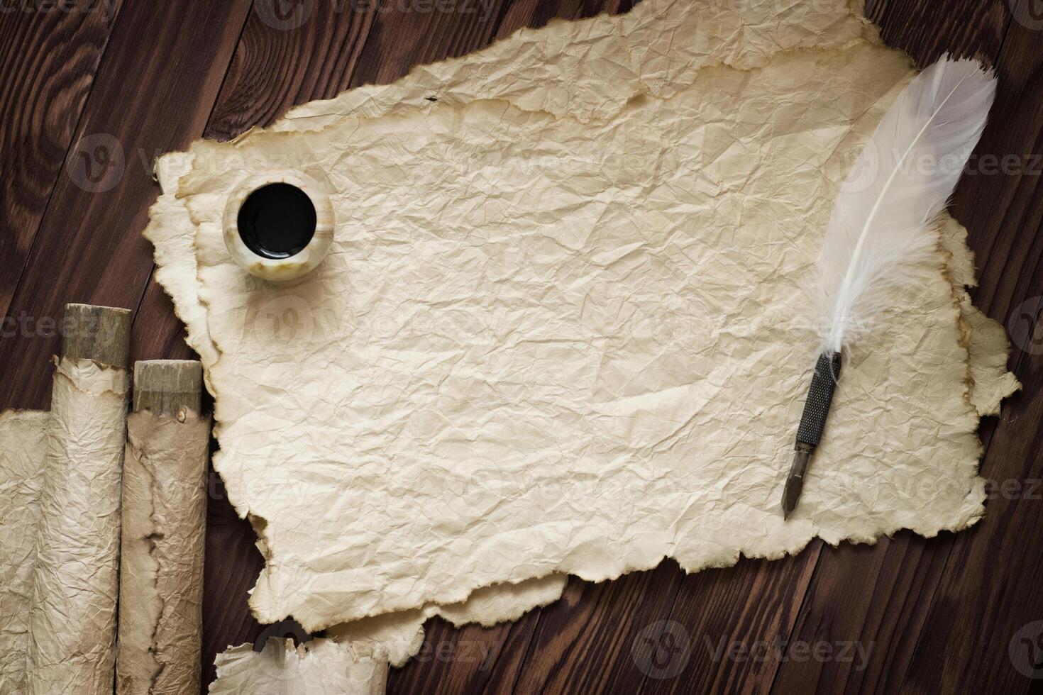 white feather and ancient scroll on brown plank photo