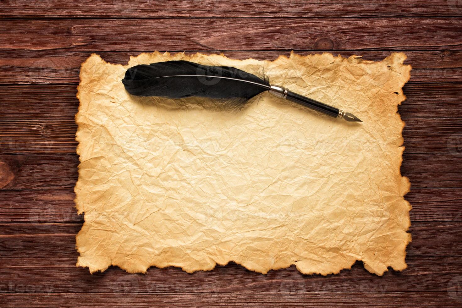 Black feather and old paper on the background of a brown table photo