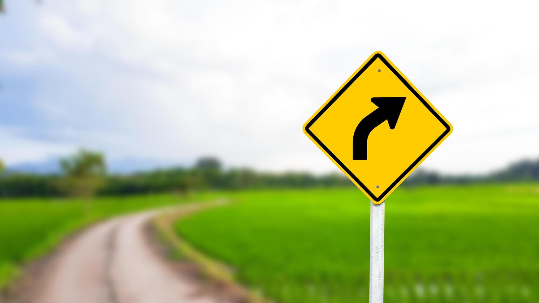 A black right-curved arrow is displayed on a bright yellow sign. photo