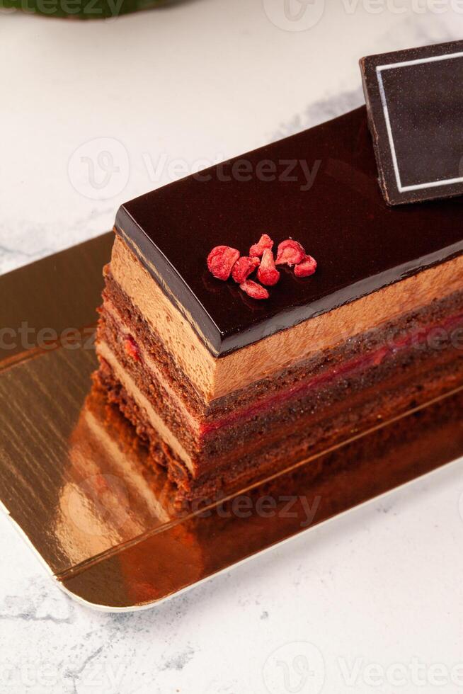 Chocolate sponge cake with mousse, raspberry confit, glaze and candied berries photo