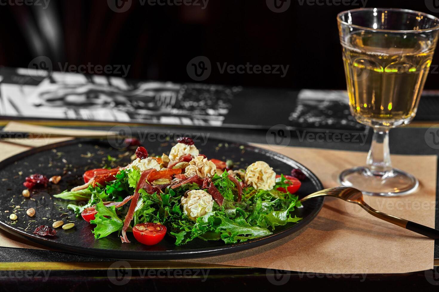 Salad of lettuce with cured jamon, cream cheese, tomatoes, dried cranberries and pumpkin seeds photo