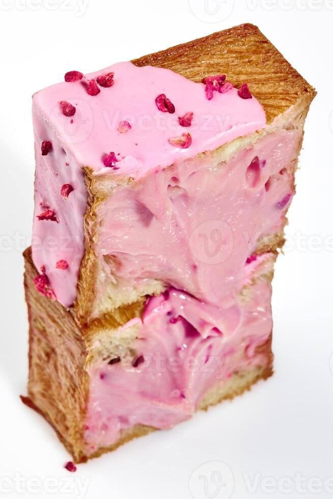 Cut in half fluffy cube shaped croissant with berry cream and candied raspberry crumble photo