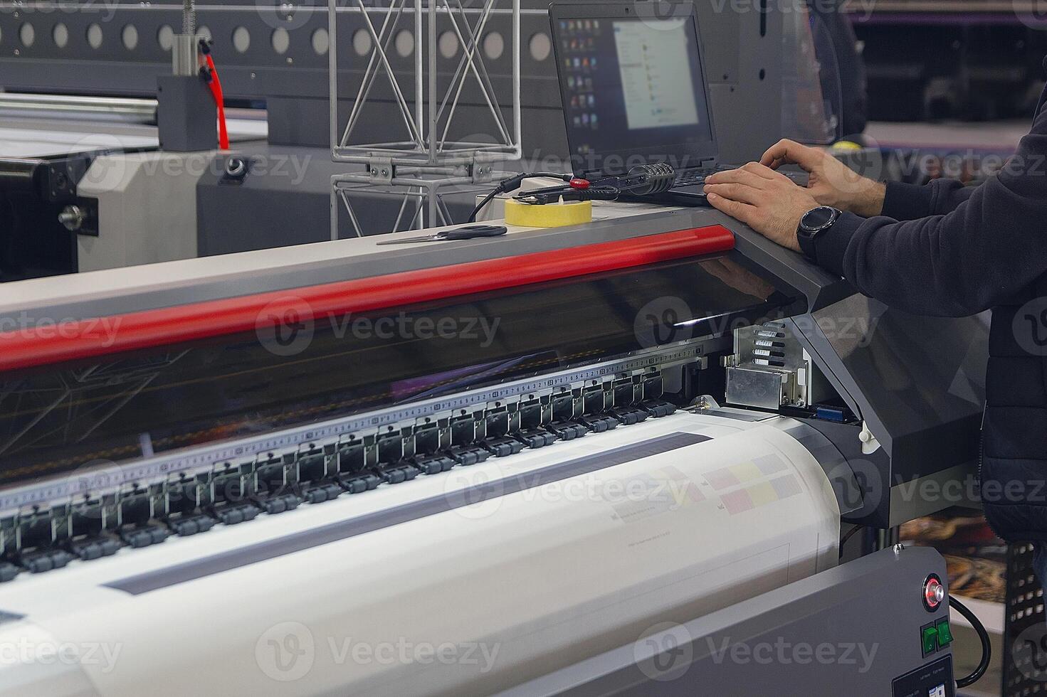 A man adjusts the printing process on a large format printing machine photo