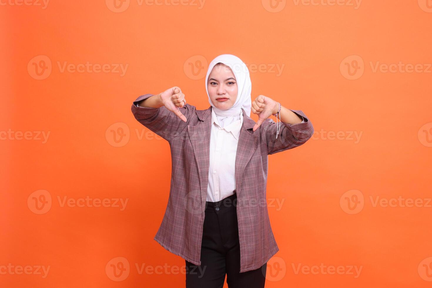 Business, finance and office, businesswoman concept. Sad indonesia businesswoman both hands thumbs down sign not good not cool isolated on orange background photo