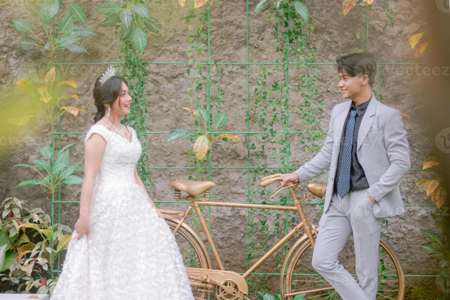 a pair of man and woman in elegant poses looking at each other romantically and affectionately wearing beautiful dresses in a park photo shot
