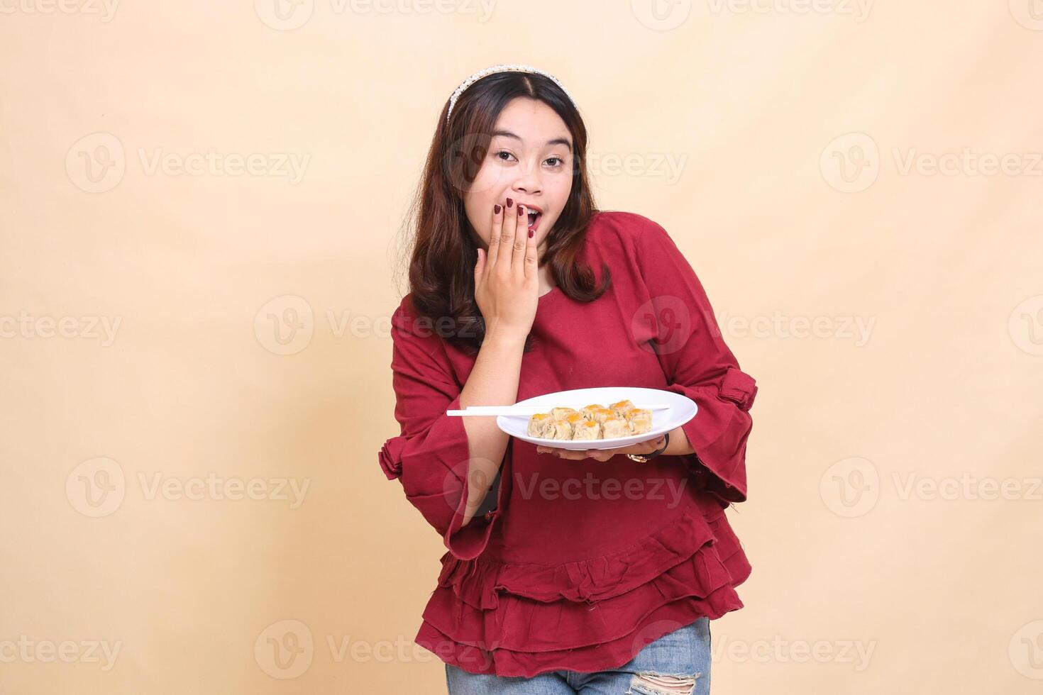 Beautiful young Asian woman in red surprised and happy carrying a plate containing dimsum Chinese food and chopsticks while serving. used for food, health and lifestyle content photo