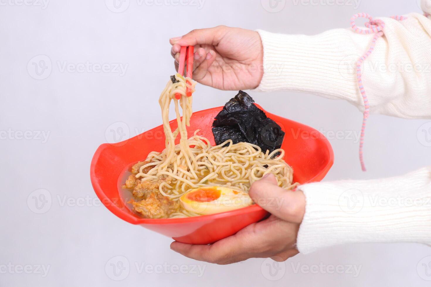 hand of asian woman in hijab carrying bowl of ramen chinese food and picking up noodles with chopsticks for advertising, food and culinary content photo