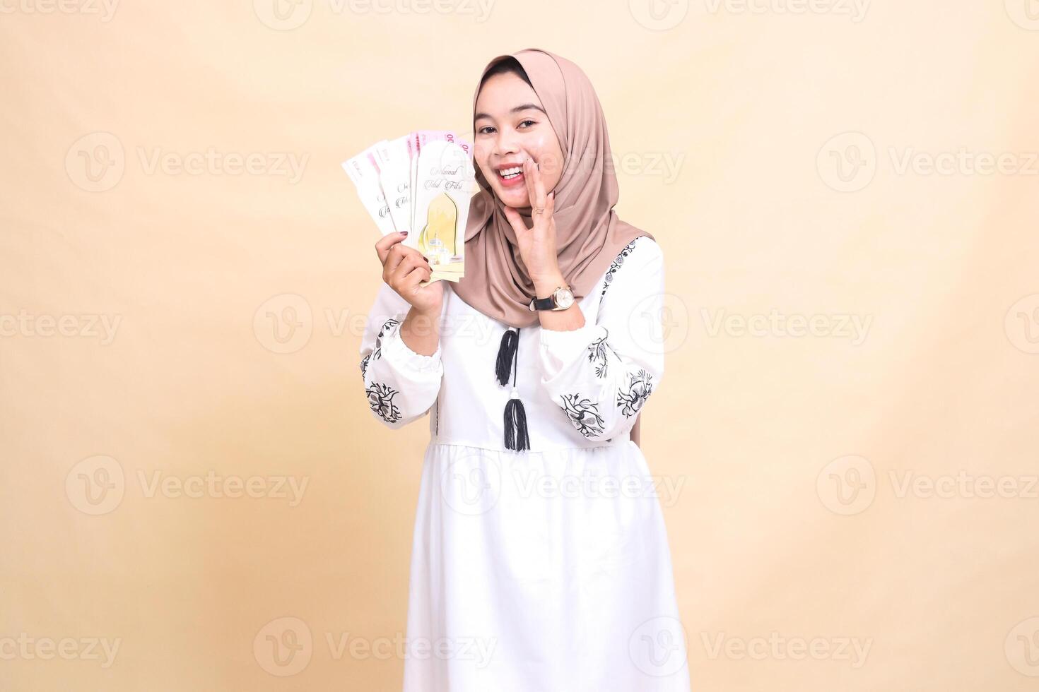 Portrait of a beautiful indonesia Muslim woman wearing a hijab, smiling and holding a smile while showing off gifts and gifts to the right on Eid. used for advertising, giveaways, Eid and Ramadan photo