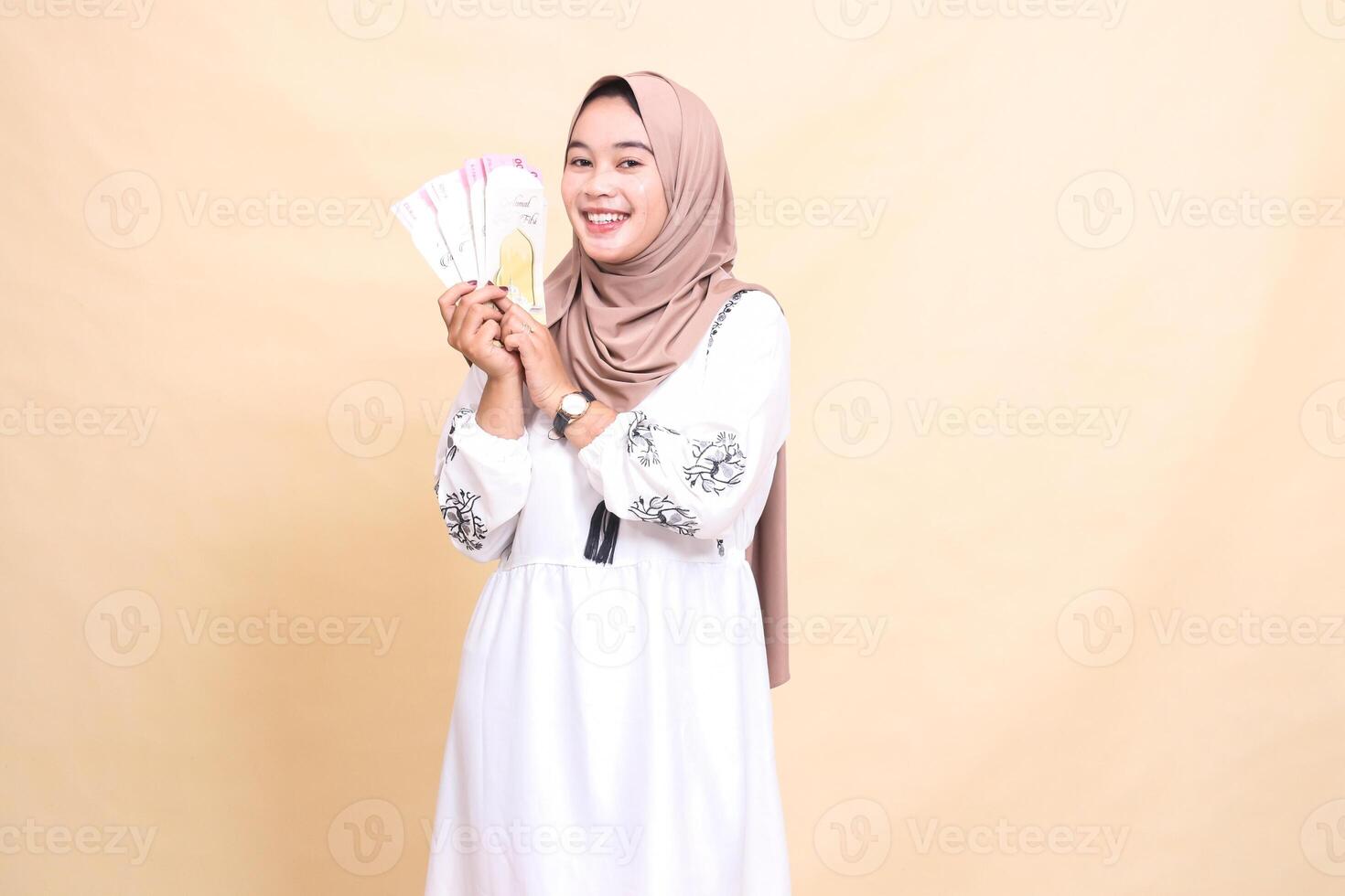 portrait of a beautiful indonesia Muslim woman wearing a cheerful hijab holding and showing off gifts and gifts to the right on Eid. used for advertising, giveaways, Eid and Ramadan photo