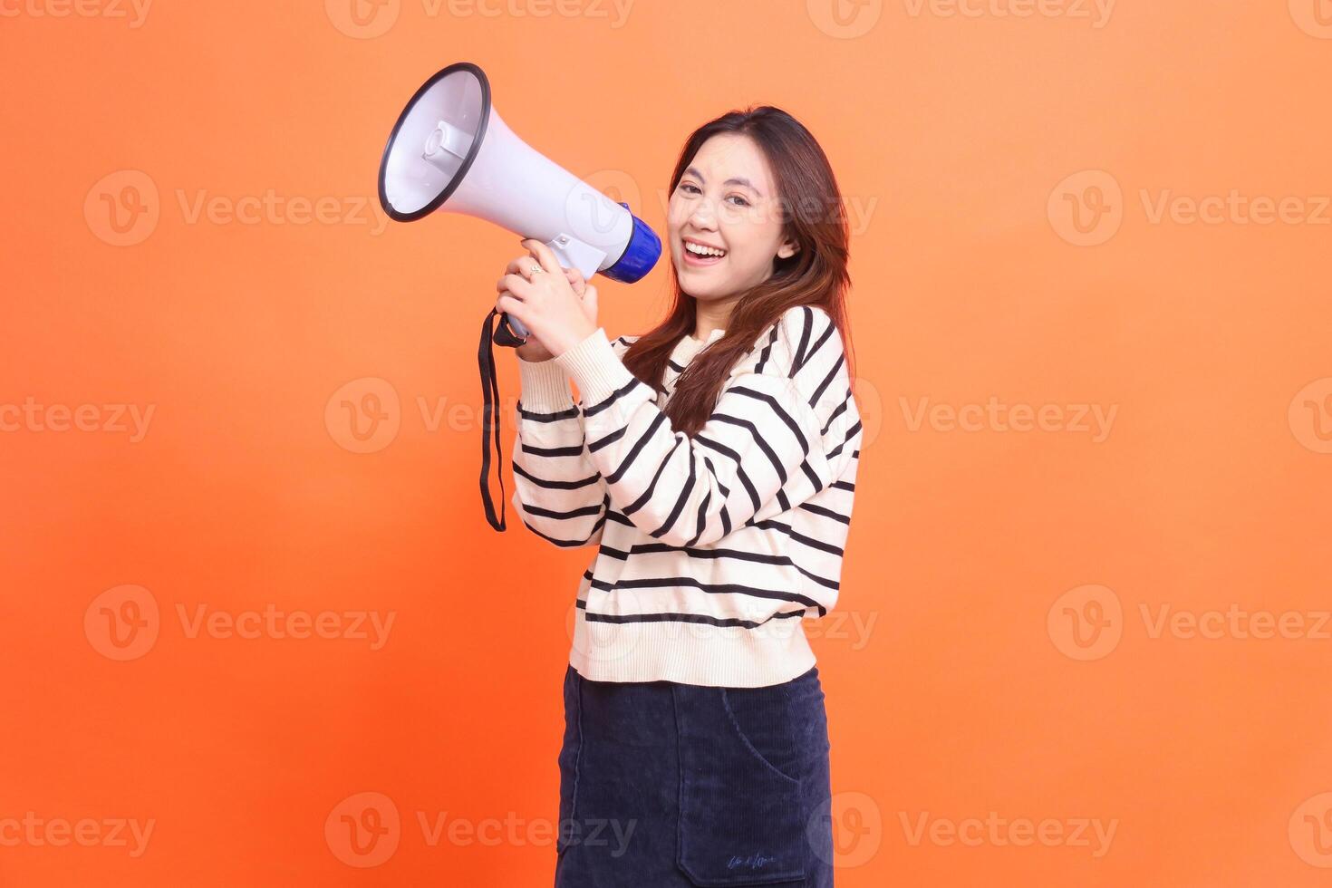 Asian woman expression shouting smile to camera standing to two hands holding megaphone loudspeaker for warning. for fashion, business and broadcast concepts photo