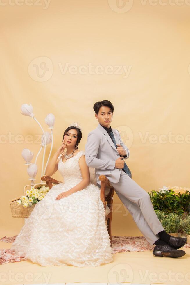 elegant male and female couple poses sitting on lounge chairs all smiling spoiled looking forward intimately indoor photo shot close up. couple wedding national bride studio