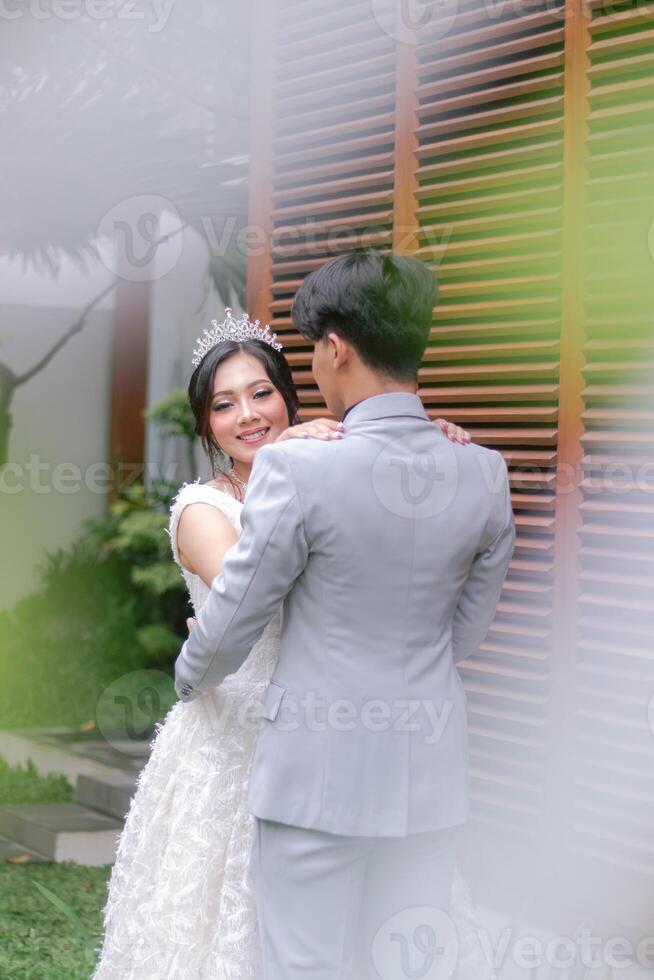 a pair of man and woman in elegant poses standing opposite a woman looking at the camera wearing a beautiful dress in a park photo shoot. national bride outdoor wedding couple