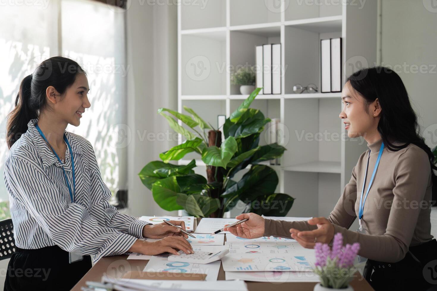 Asian businesswomen discussing work at a table in a modern office. Concept of collaboration, teamwork, and strategy photo