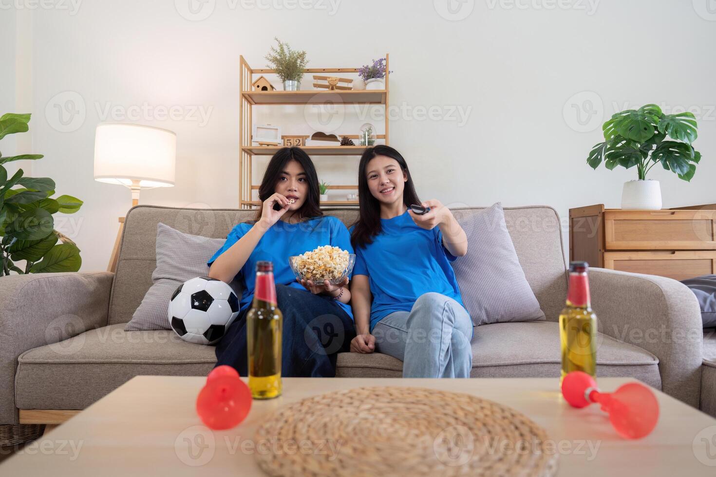 Lesbian couple cheering for Euro football at home with popcorn and drinks. Concept of sports enthusiasm and LGBTQ pride photo