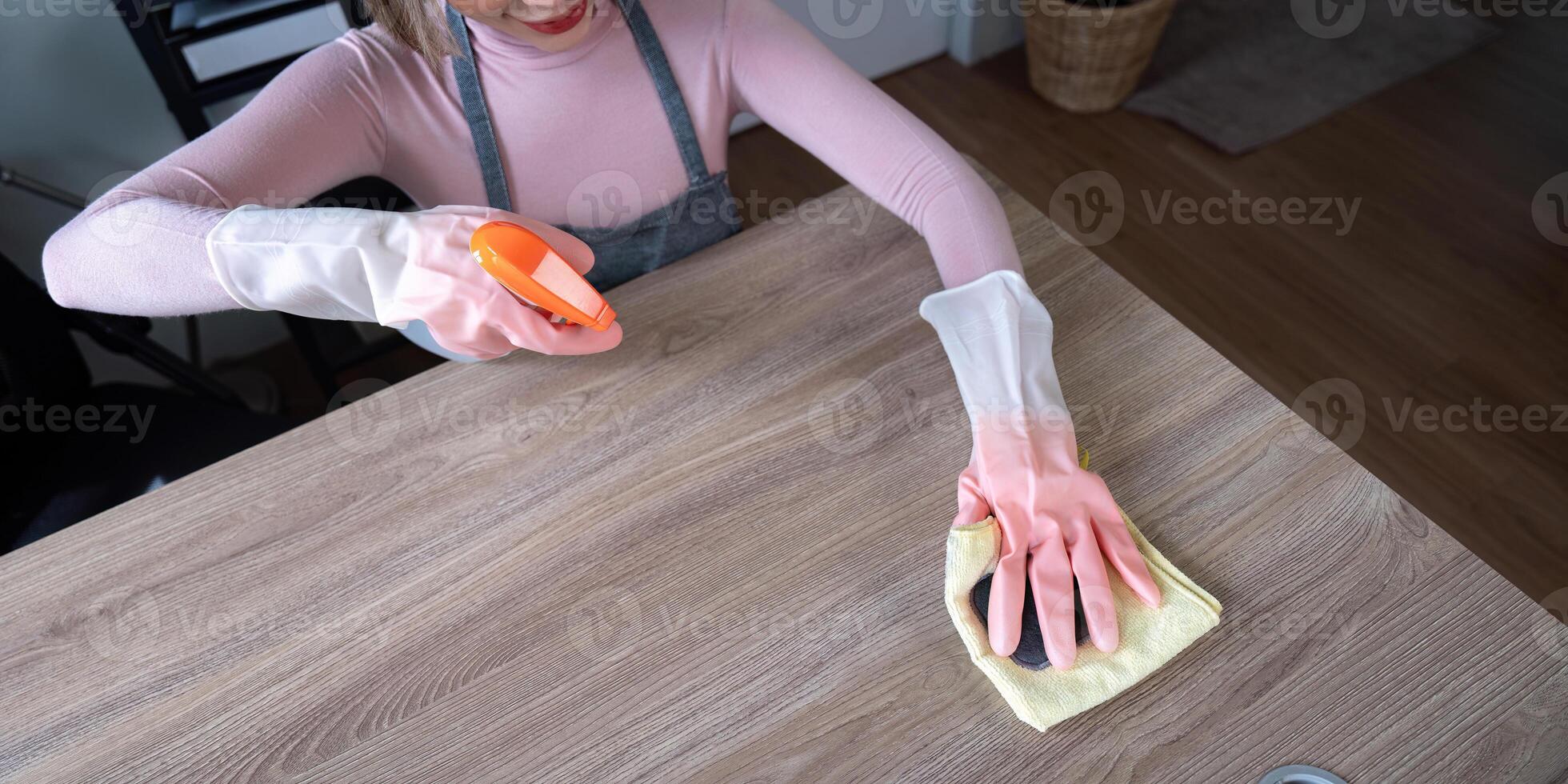 Housekeeper Cleaning Wooden Table with Spray Bottle and Cloth in Modern Home Interior photo