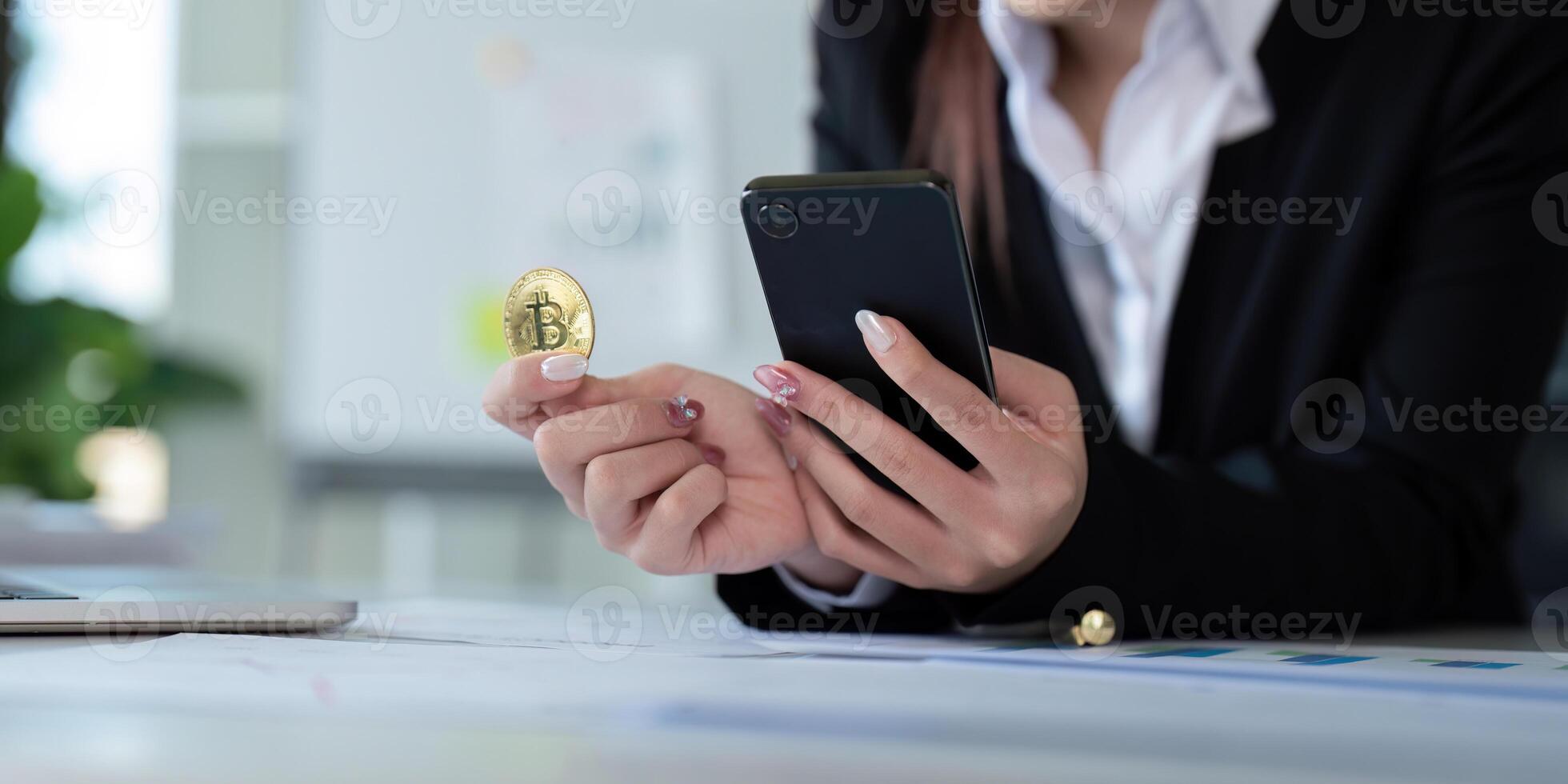 Businesswoman holding a golden bitcoin. using Mobile with graph chart, trading stock market, investing Bitcoin cryptocurrency at home office. Investment and technology concept photo