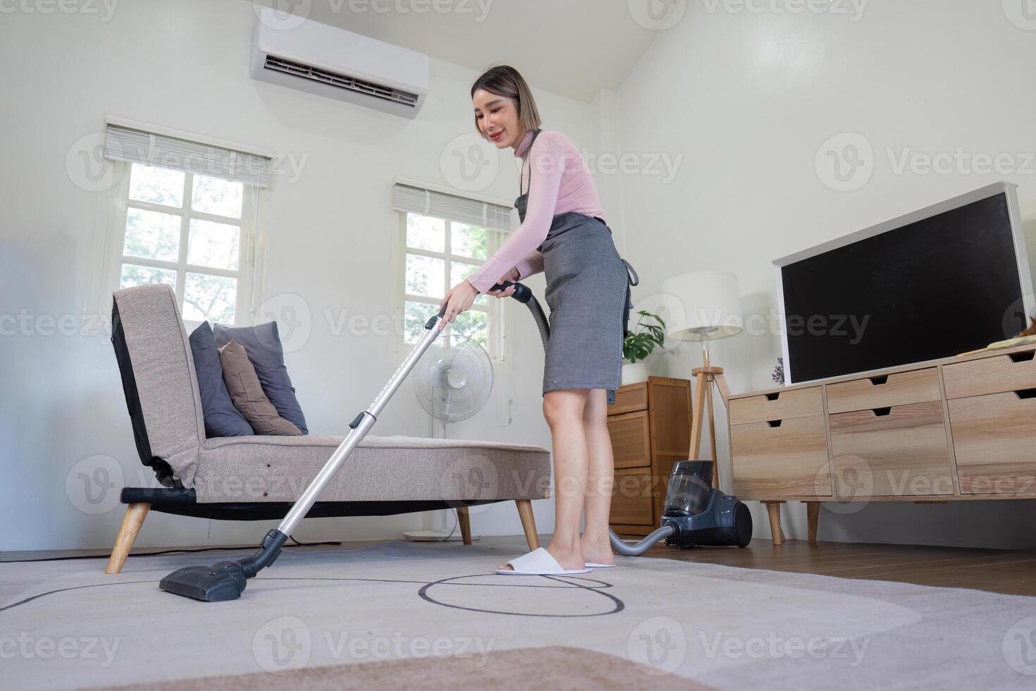 Housekeeper Cleaning Modern Living Room with Vacuum Cleaner in Bright and Tidy Home Interior photo