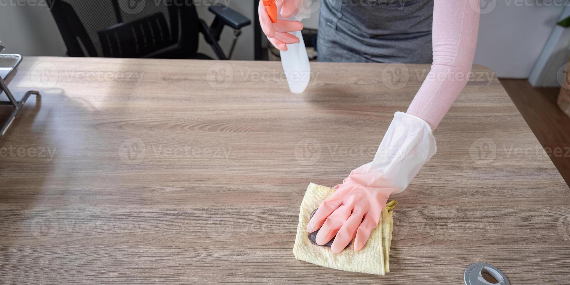 Housekeeper Cleaning Wooden Table with Spray Bottle and Cloth in Modern Home Interior photo