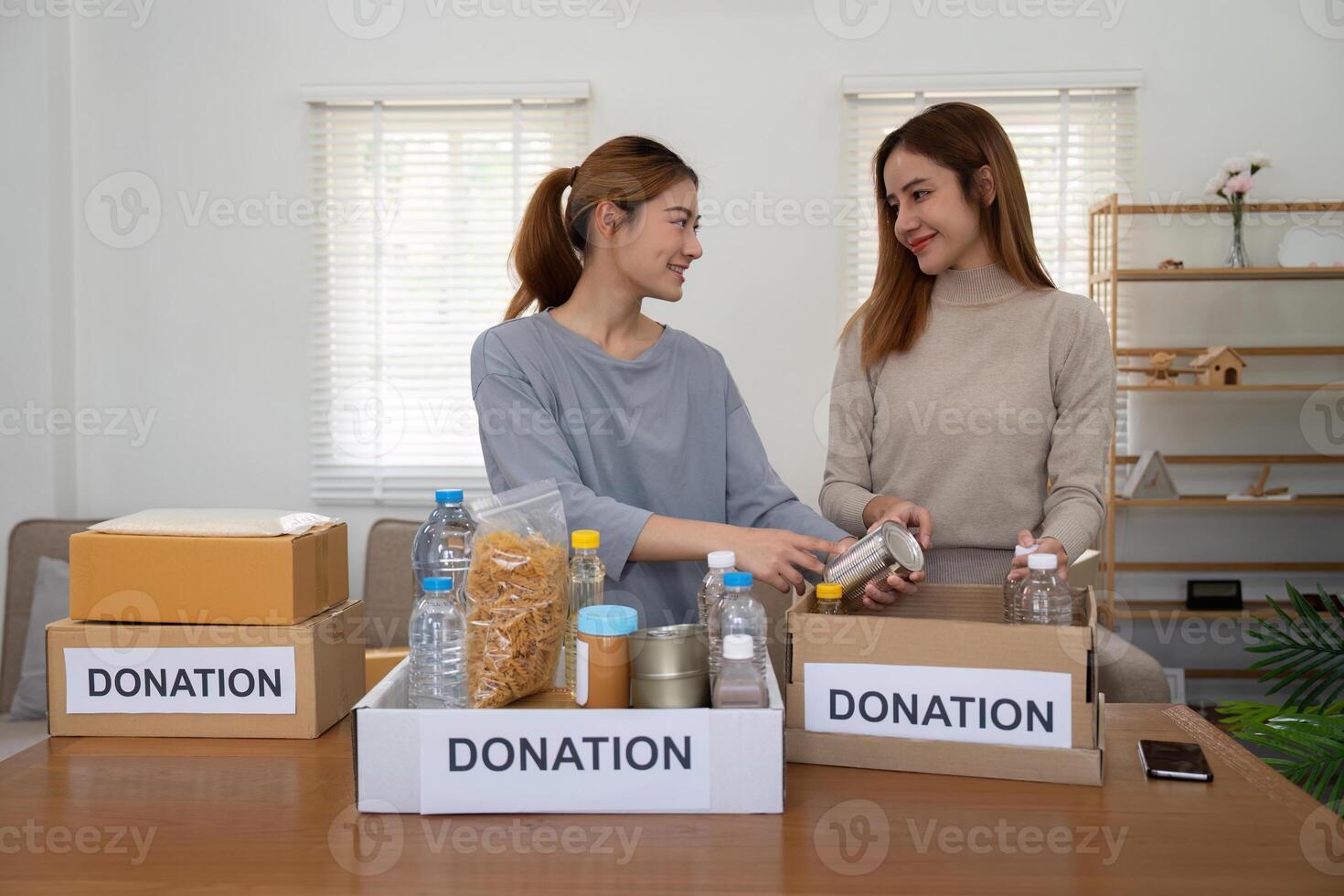 Happy young woman volunteer collecting, sorting food for needy people, team working together on donation project in charitable at home photo