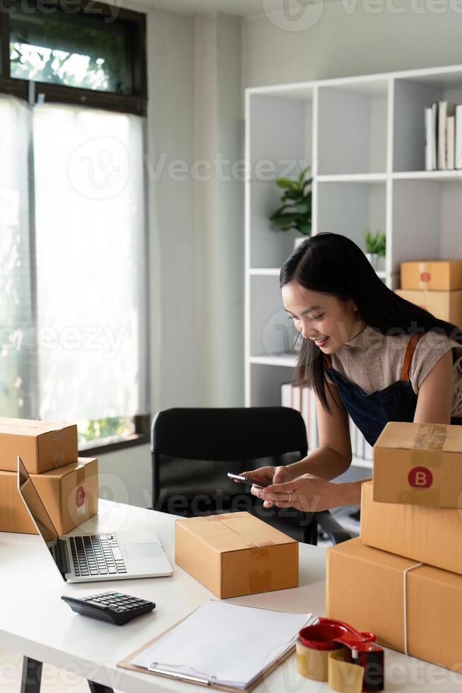 Young women taking photo product with cell telephone or smartphone digital camera for post to sell online on the Internet and preparing pack product box. Selling online ideas concept