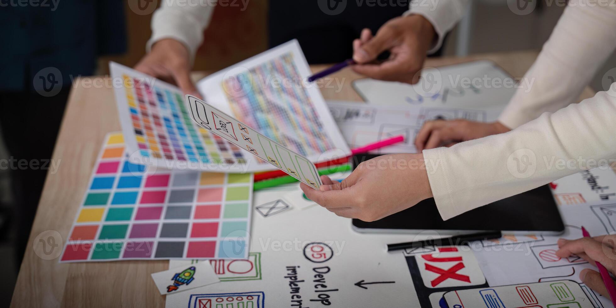 UX Developer and UI Designer Brainstorming Session with Color Palettes and Wireframes on Desk photo