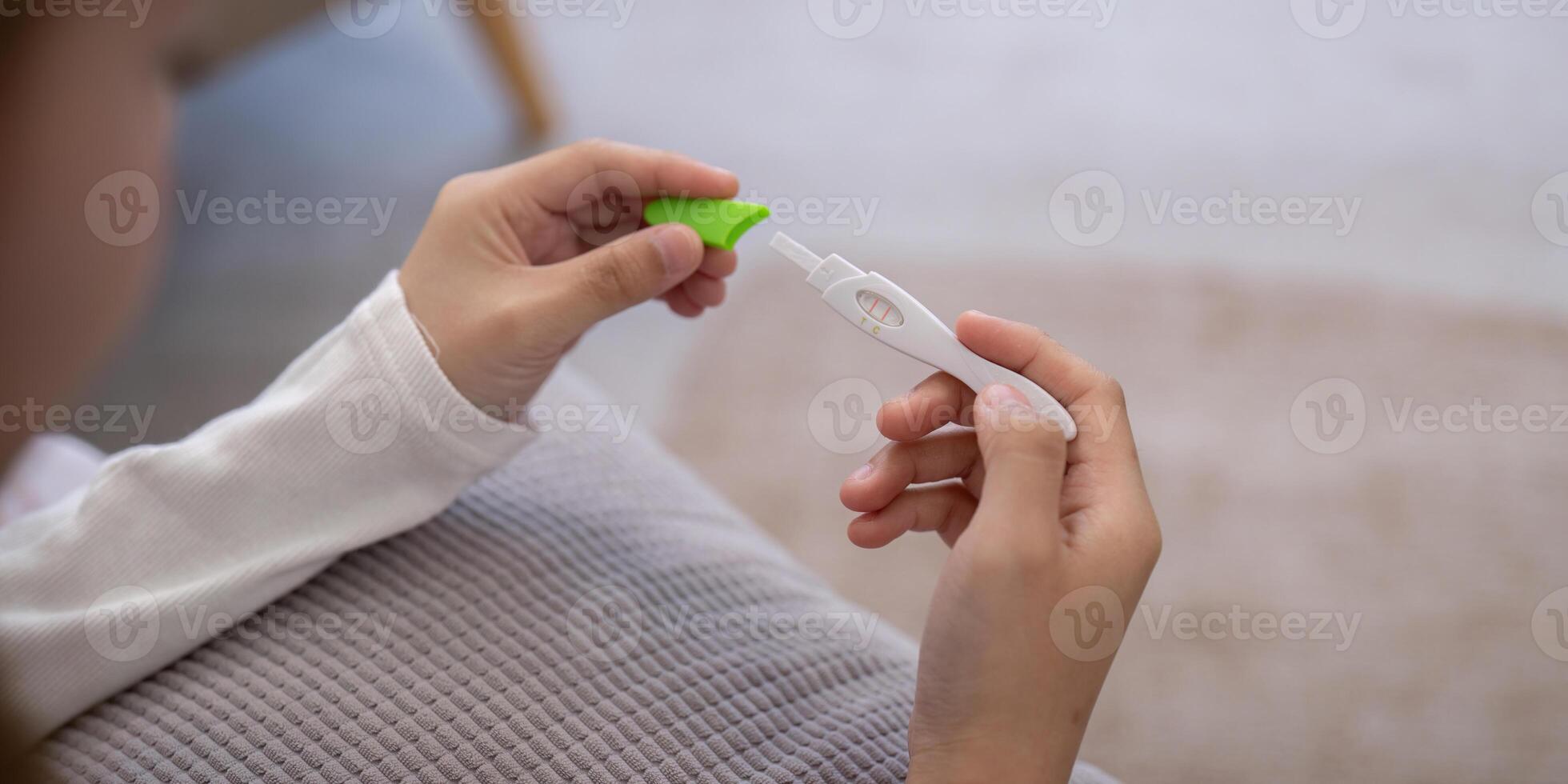 Close Up of Hands Holding a Pregnancy Test Kit with Positive Result in a Cozy Home Setting photo