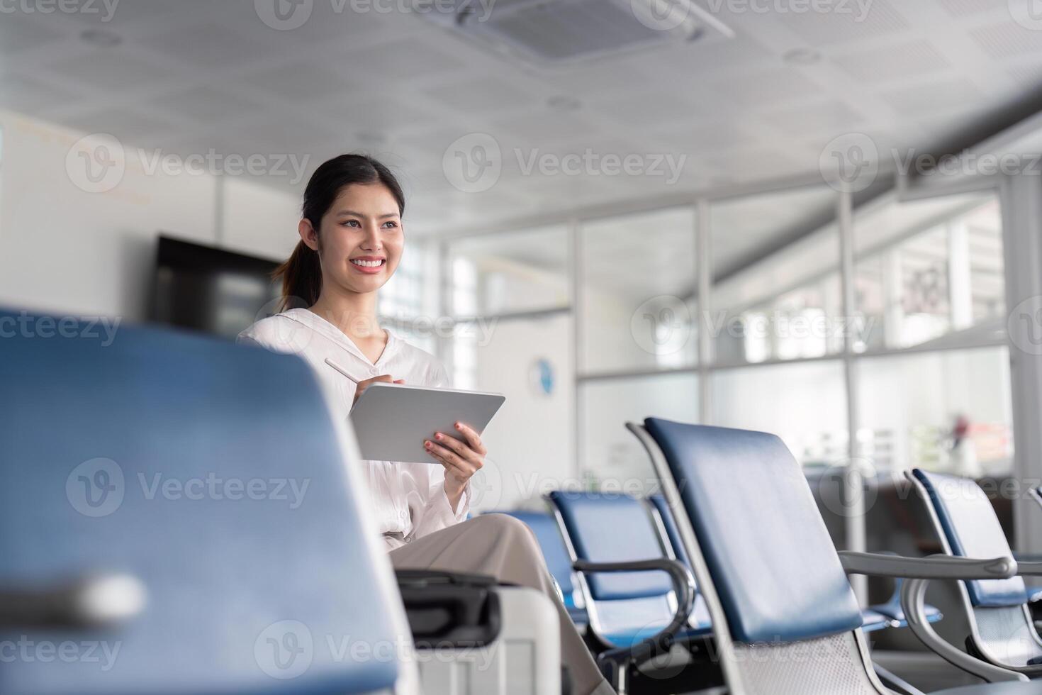 Businesswoman Professional Using Tablet in Modern Airport Lounge with Glass Partitions and Comfortable Seating photo