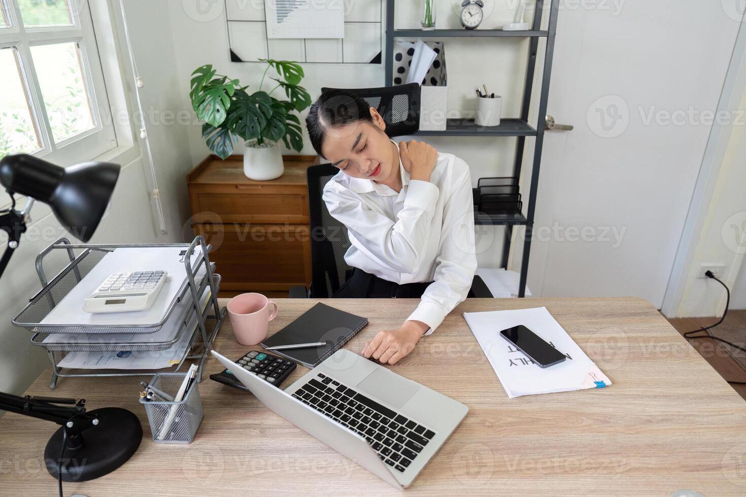 Business Professional Experiencing Neck Pain While Working at Desk in Modern Office Setting photo