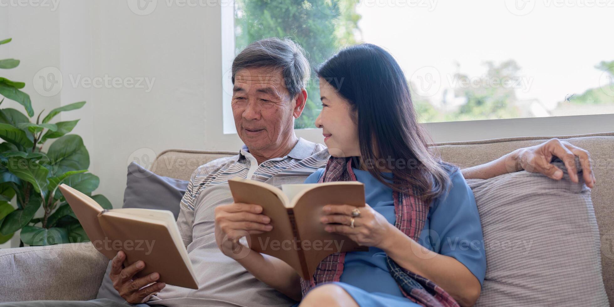 Elderly Couple Enjoying Quality Time Reading Books Together on a Cozy Sofa in a Bright Living Room photo