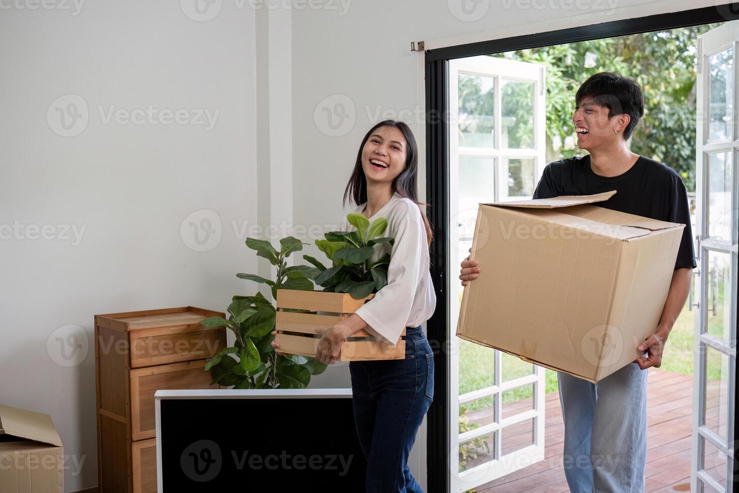 Happy Couple Moving into New Home Carrying Boxes and Plants, Smiling and Enjoying Fresh Start in Bright Modern House photo