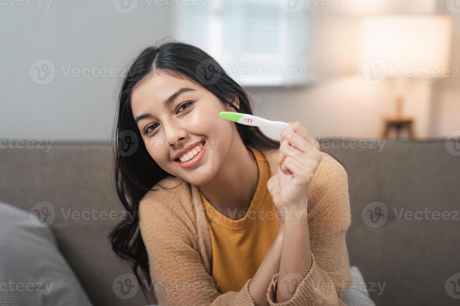 Happy Woman Holding Positive Pregnancy Test, Celebrating Exciting News, Joyful Expectant Mother, Home Setting, Bright Future photo