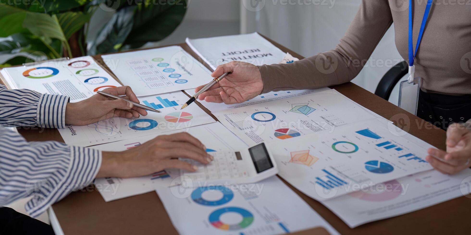 Two Business Professional Discussing Planning and Analysis with Charts and Graphs in a Modern Office Setting photo