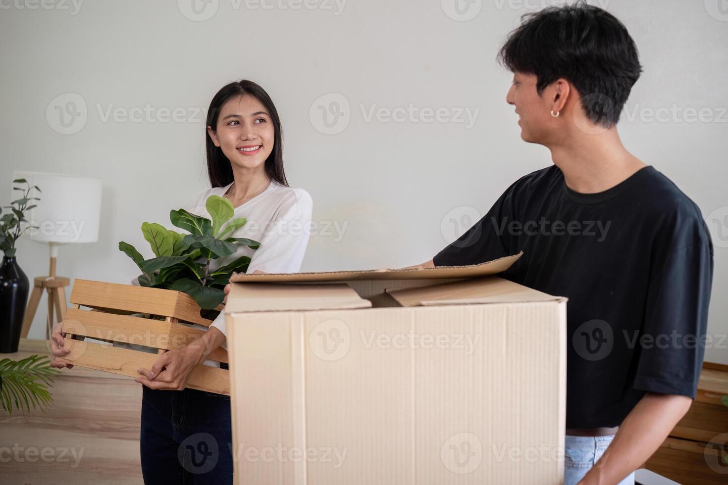 Young Couple Moving into New House, Carrying Boxes and Plants, Starting Fresh in Their New Home, Excited and Happy, Unpacking and Decorating, Beginning a New Chapter Together, Modern Living Space photo