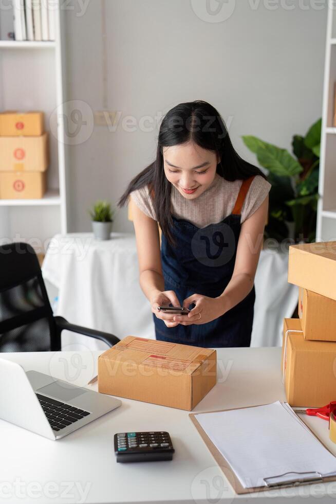 Young Woman Preparing Parcel Boxes for Online Business with Laptop and Calculator in Modern Workspace photo