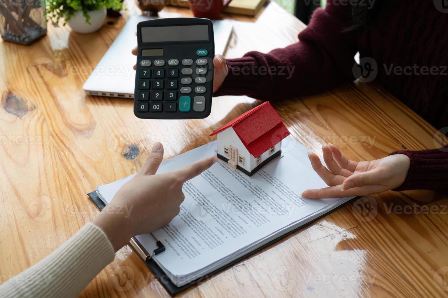 Real Estate Agent Presenting Home Insurance Options with Calculator and House Model on Wooden Desk photo