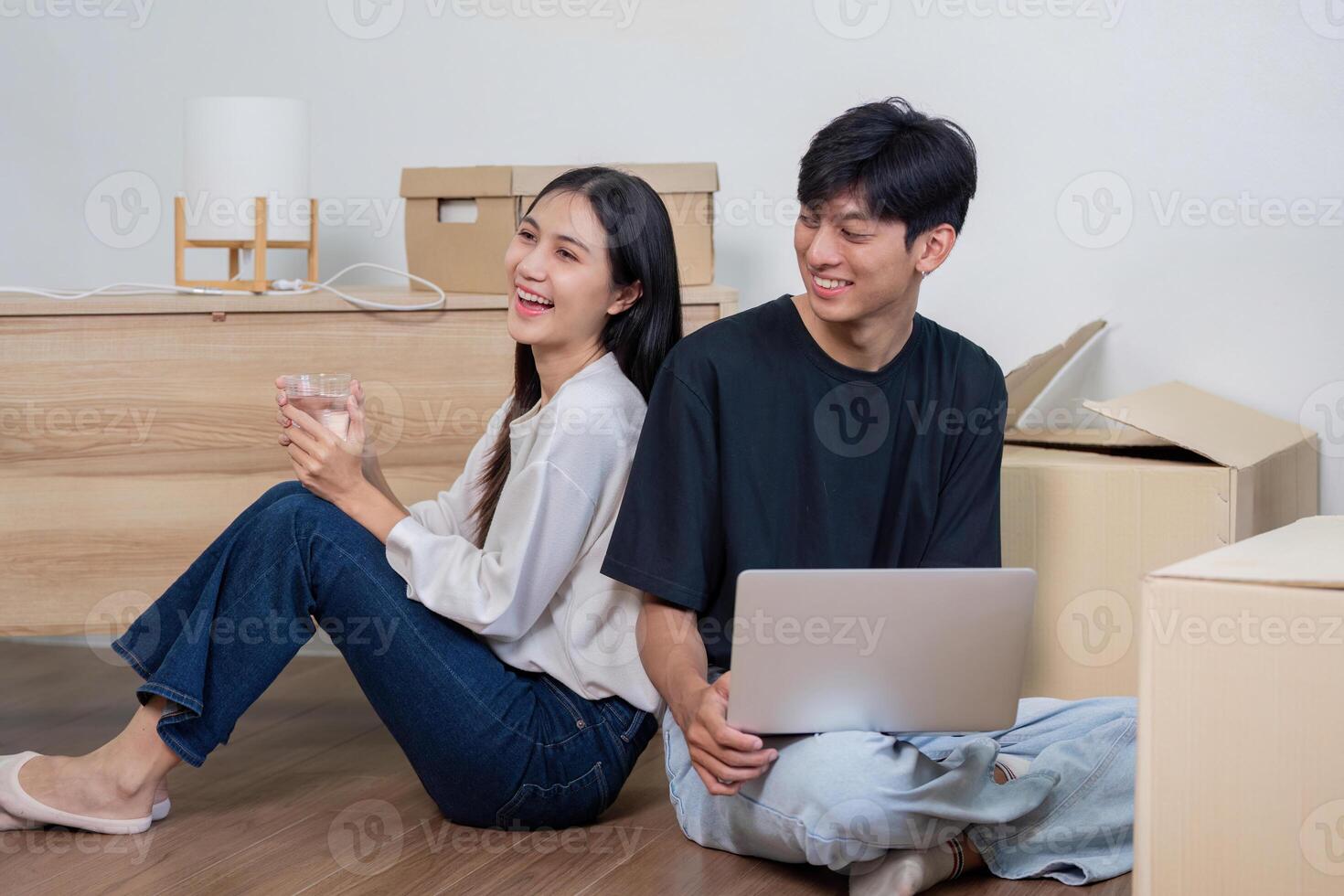 Happy Couple Relaxing in Their New Home Surrounded by Moving Boxes, Enjoying a Break During the Moving Process photo