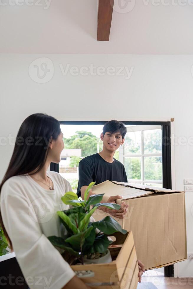 Young Couple Moving into New House Carrying Boxes and Plants in Bright Modern Home photo