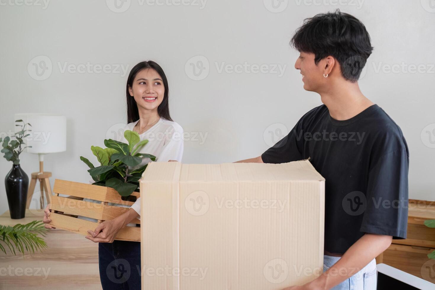 Young Couple Moving into New House, Carrying Boxes and Plants, Starting Fresh in Modern Home photo