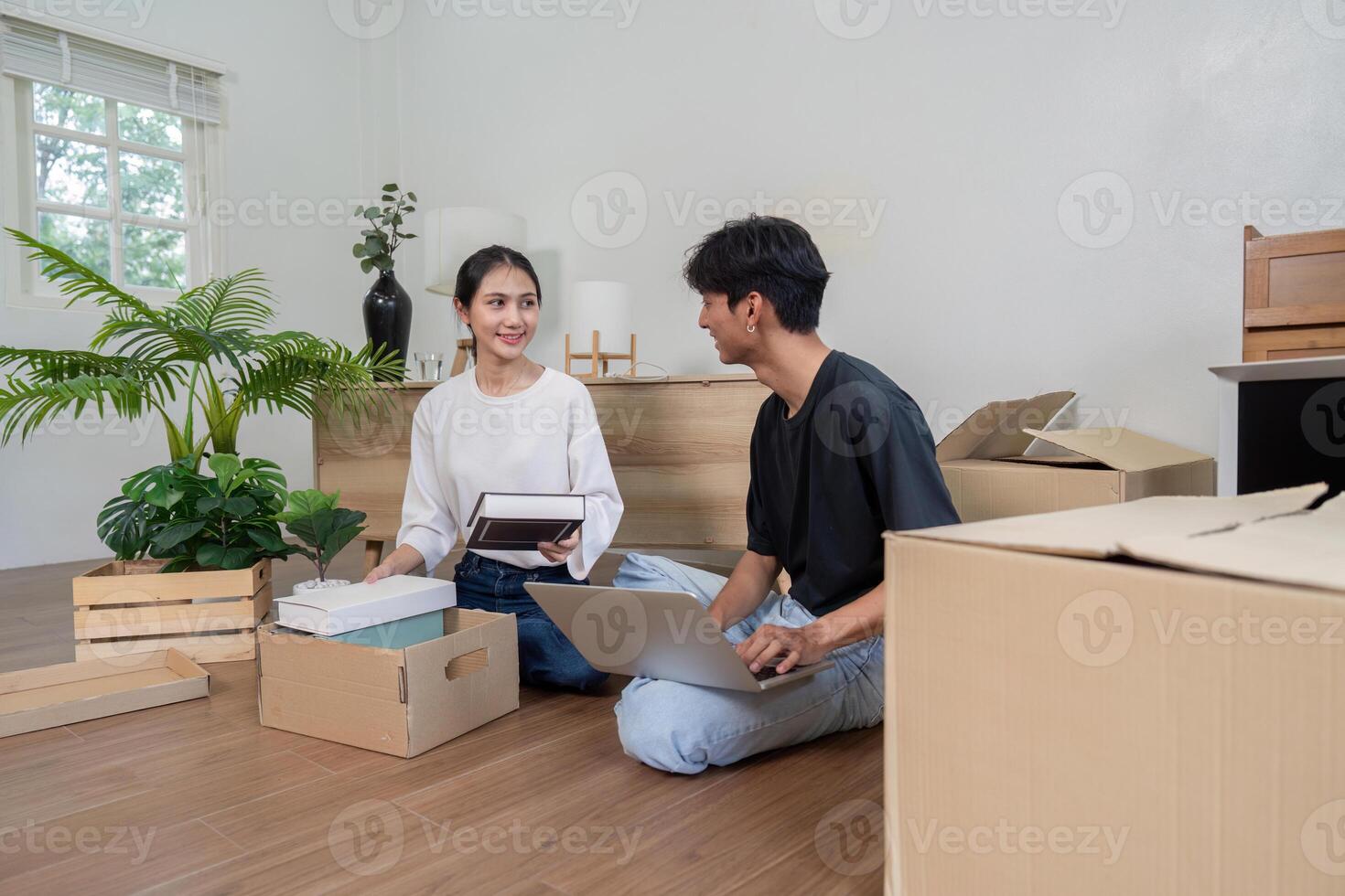 joven Pareja desempacar cajas en su nuevo hogar, sonriente y organizando pertenencias en un brillante moderno vivo habitación foto