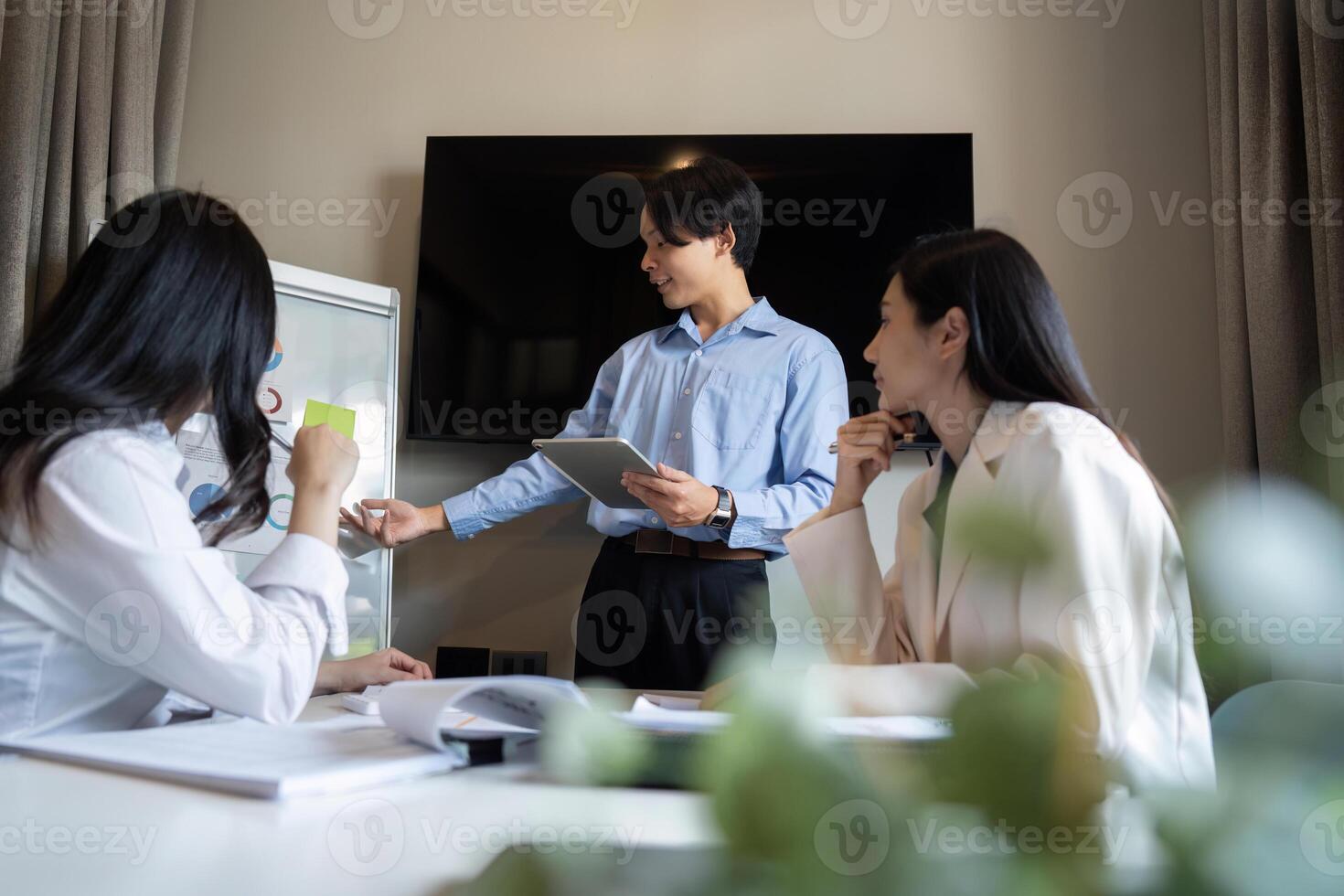 Business Team Engaged in Analysis Discussion in Modern Office Setting with Digital Devices and Whiteboard photo