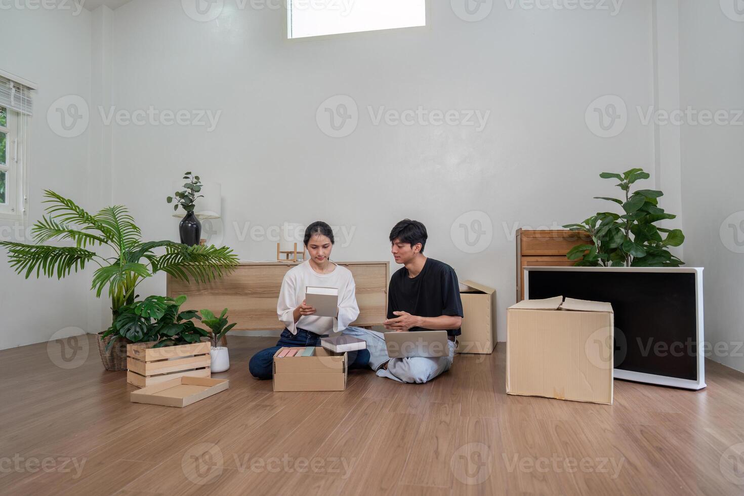 Young Couple Unpacking Boxes in Their New Home with Modern Interior and Green Plants photo