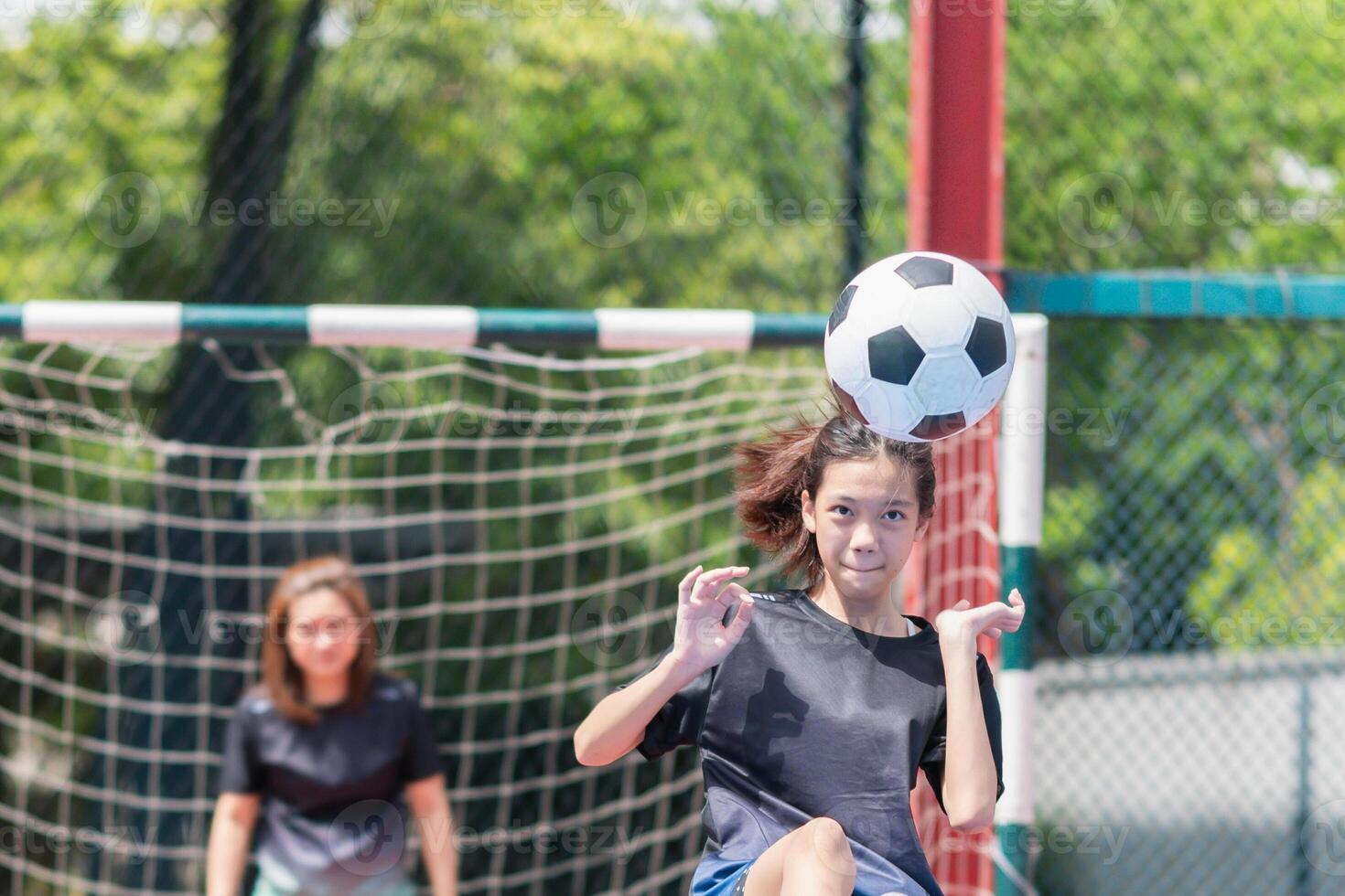 Mom with a child playing football in the urban outdoor futsal court photo