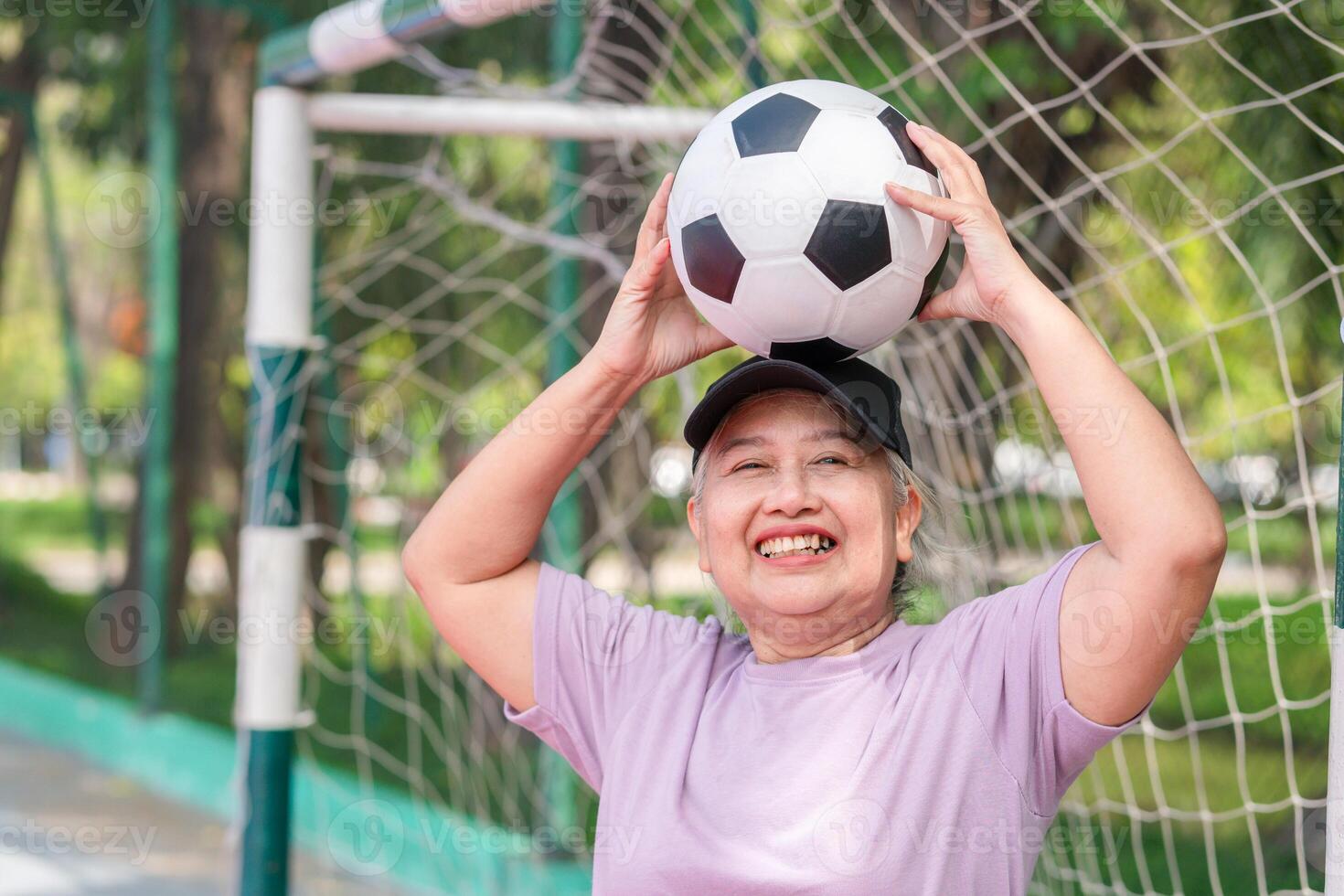 Active senior woman playing football in the urban outdoor court, Asian senior woman with a soccer ball, healthy life concepts photo