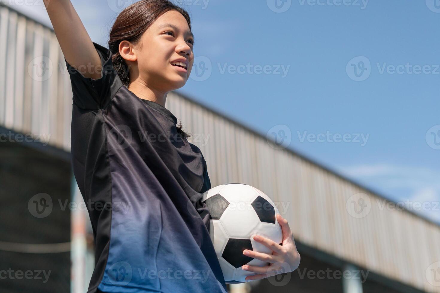 Excited Asian kid girl holding a football celebrates photo