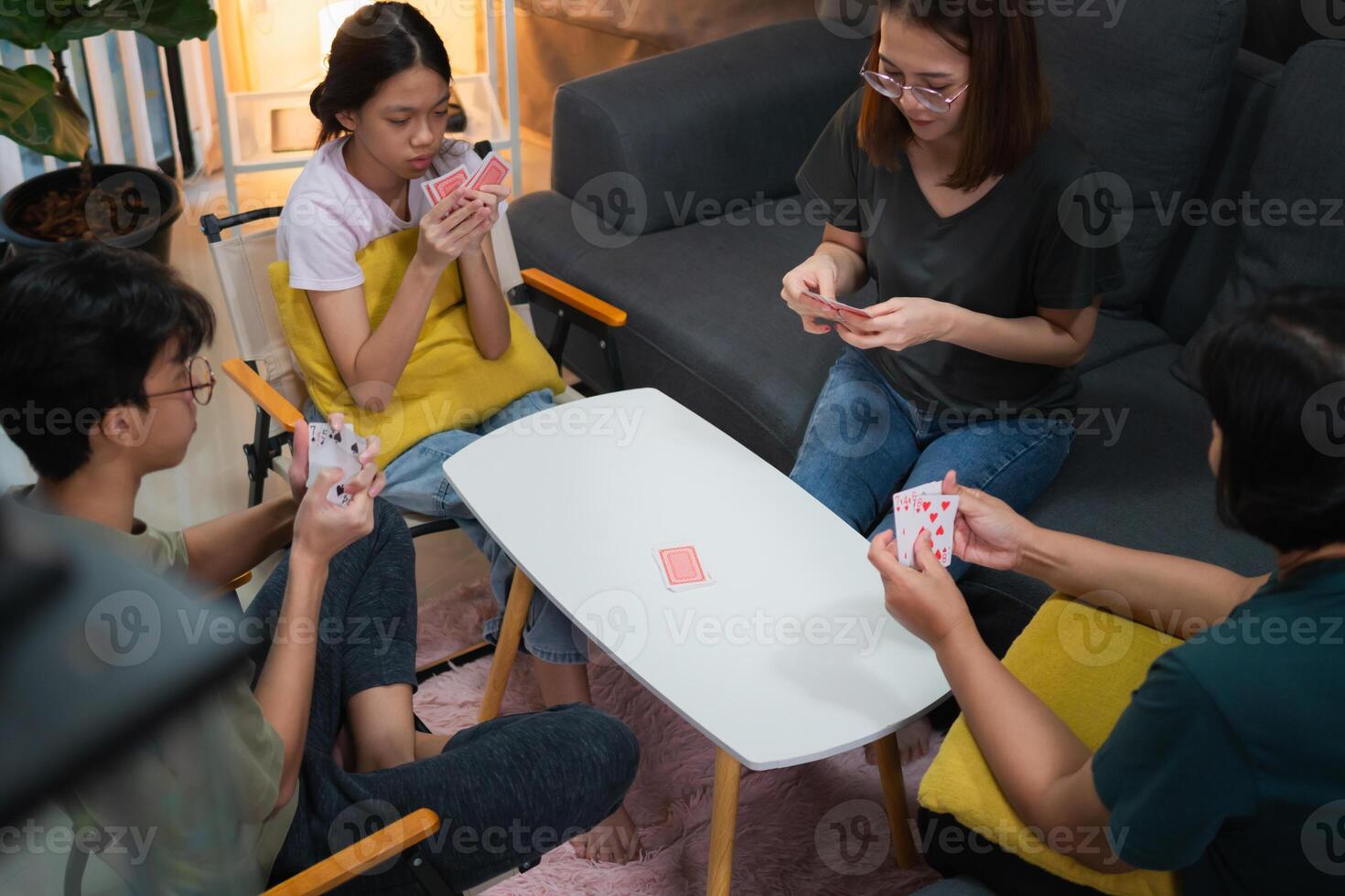 Asian family playing games together, Diverse people playing a card game in the living room photo