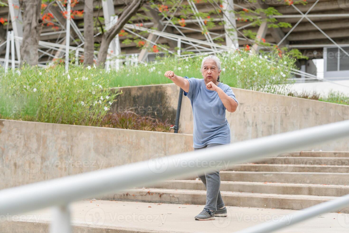Asian senior sportswoman boxing while working out on parking outdoors photo