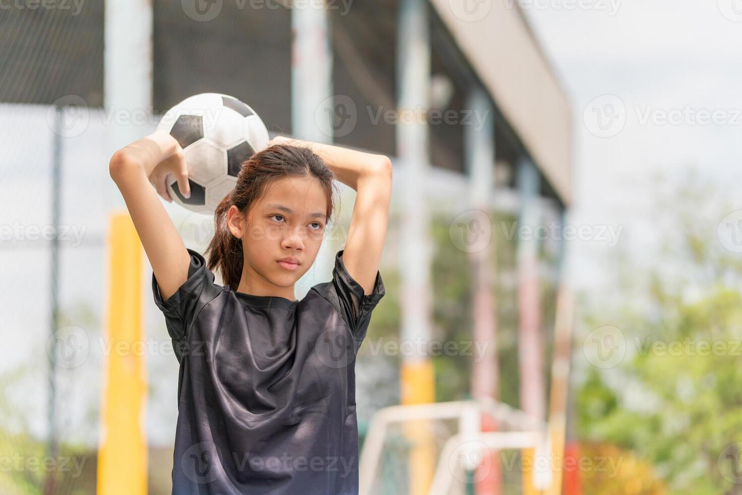 Child girl playing with a soccer ball, Asian kid girl playing football in the urban outdoor futsal court photo